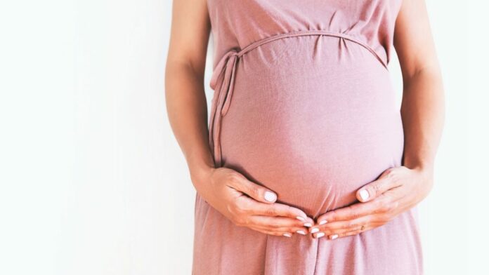 pregnant woman wearing pink holding her belly 1024x576 1